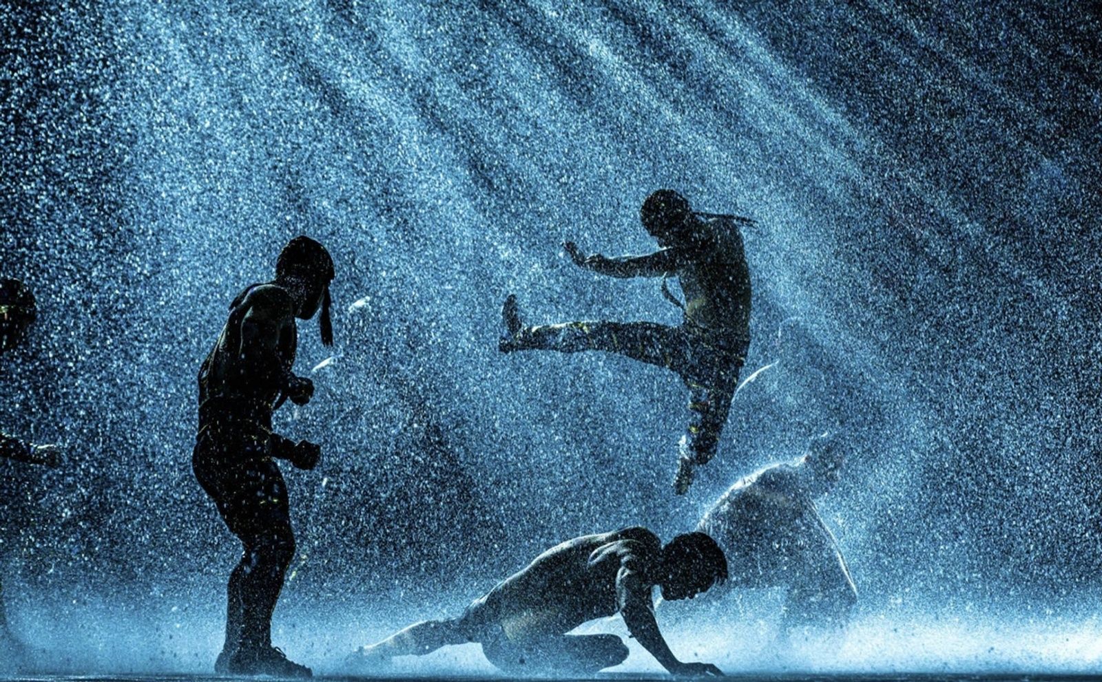 Silhouetted dancers perform in the rain during The House of Dancing Water