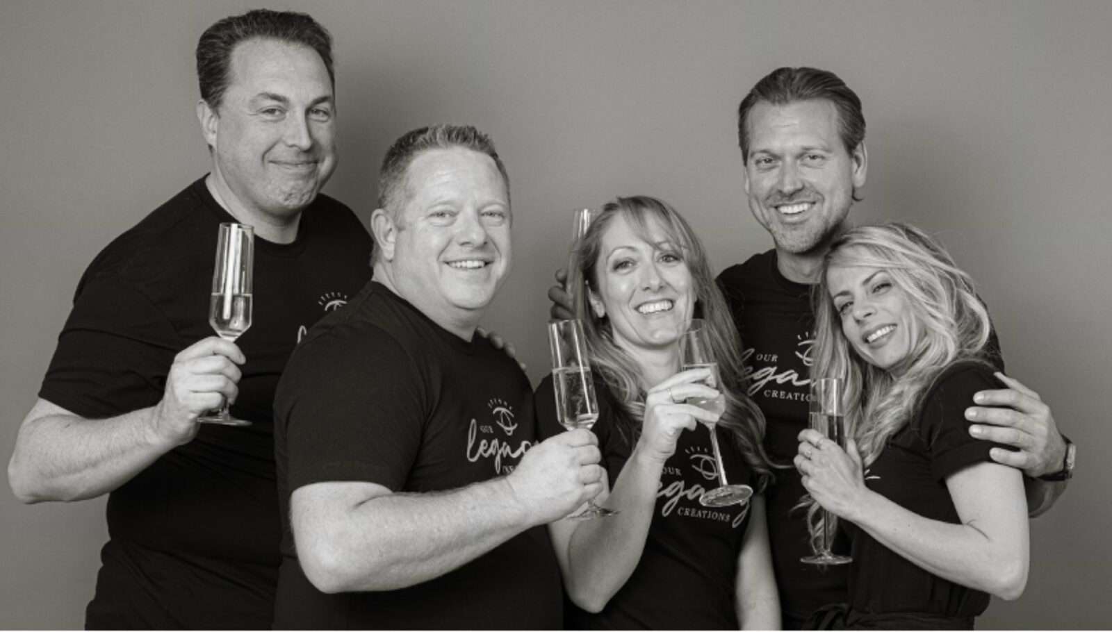 OLC founding members in black t-shirts smiling with champagne flutes.